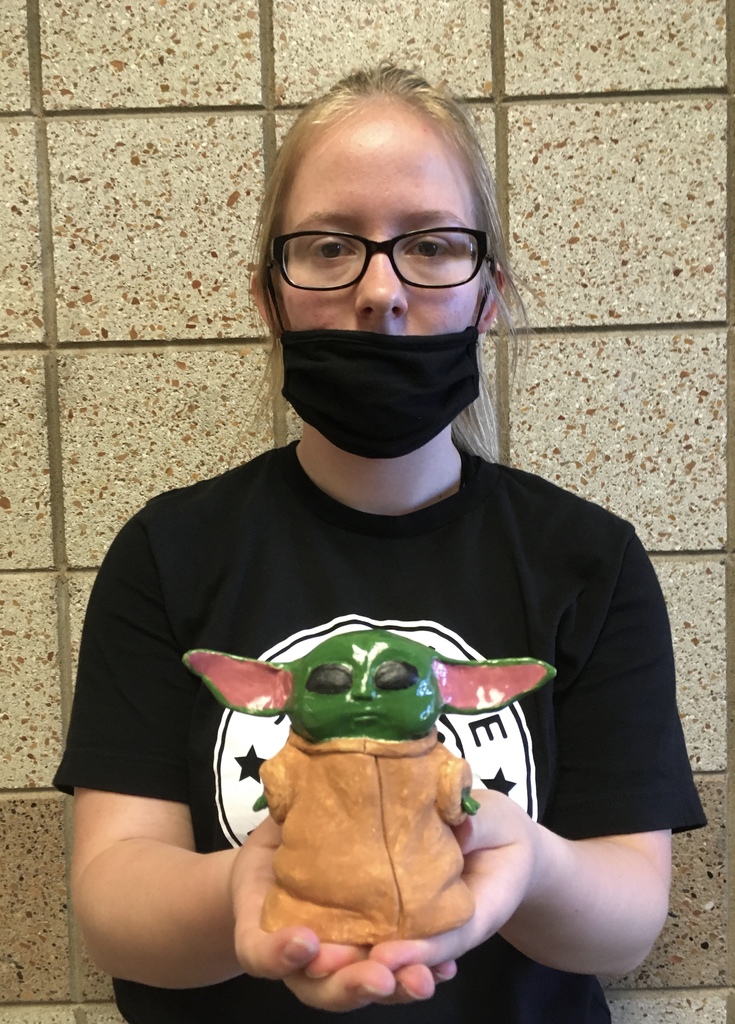 student with a mask holding a baby Yoda clay