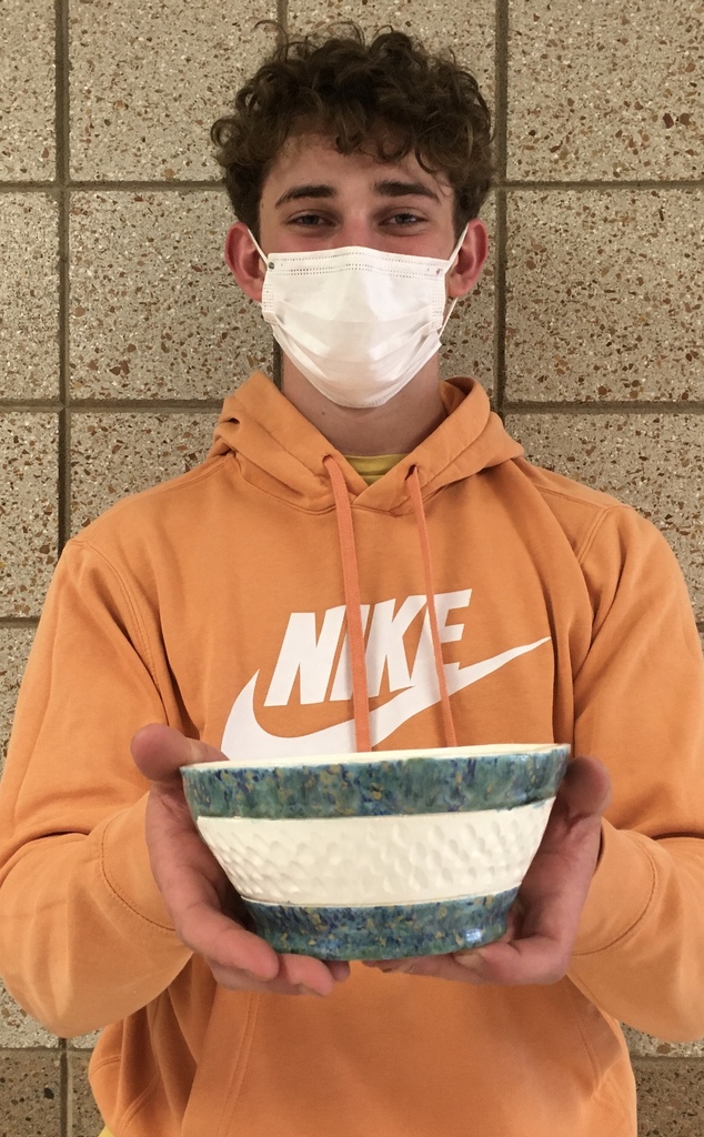 male student with a mask holding a clay bowl