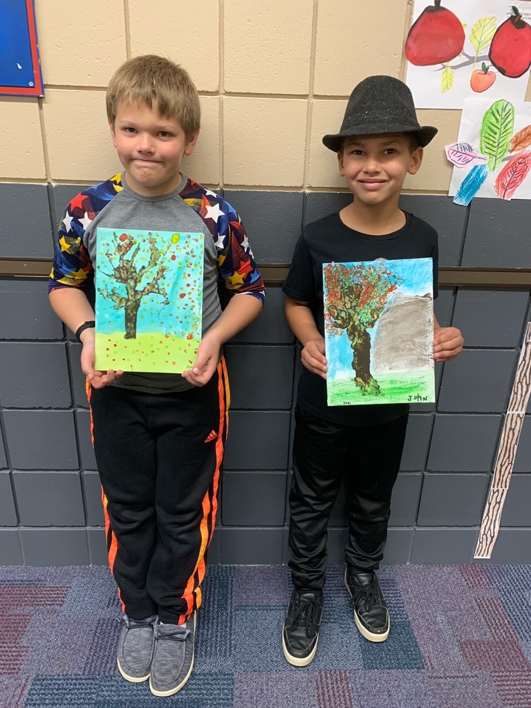 two students holding their tree painting
