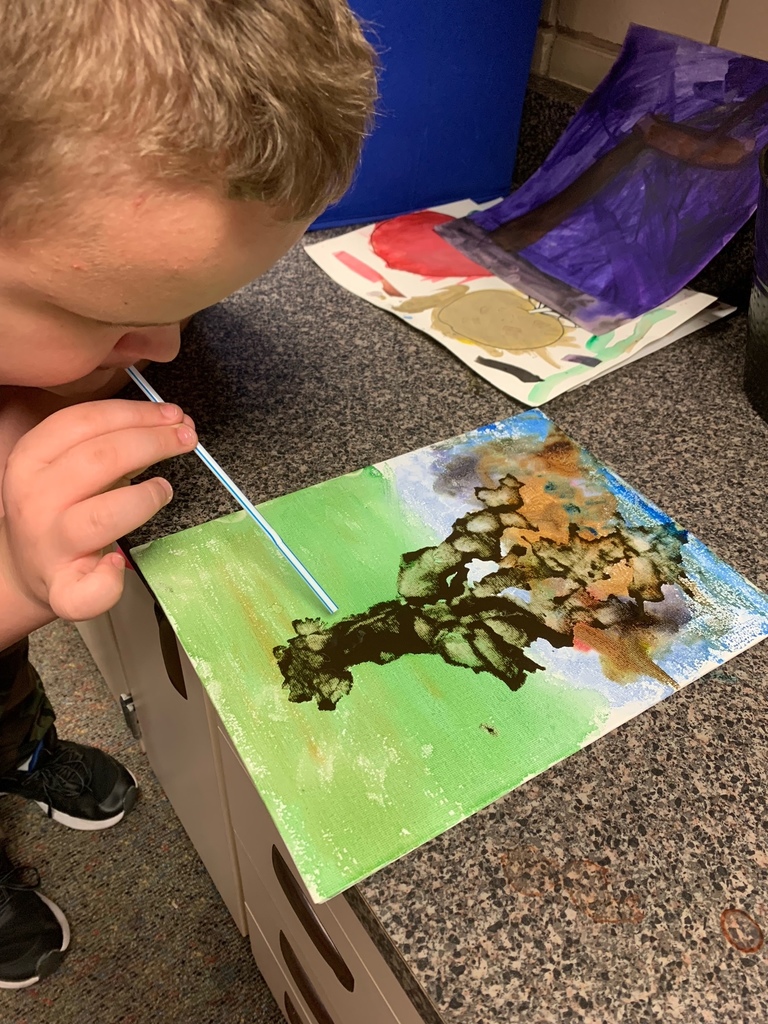 student painting with a straw
