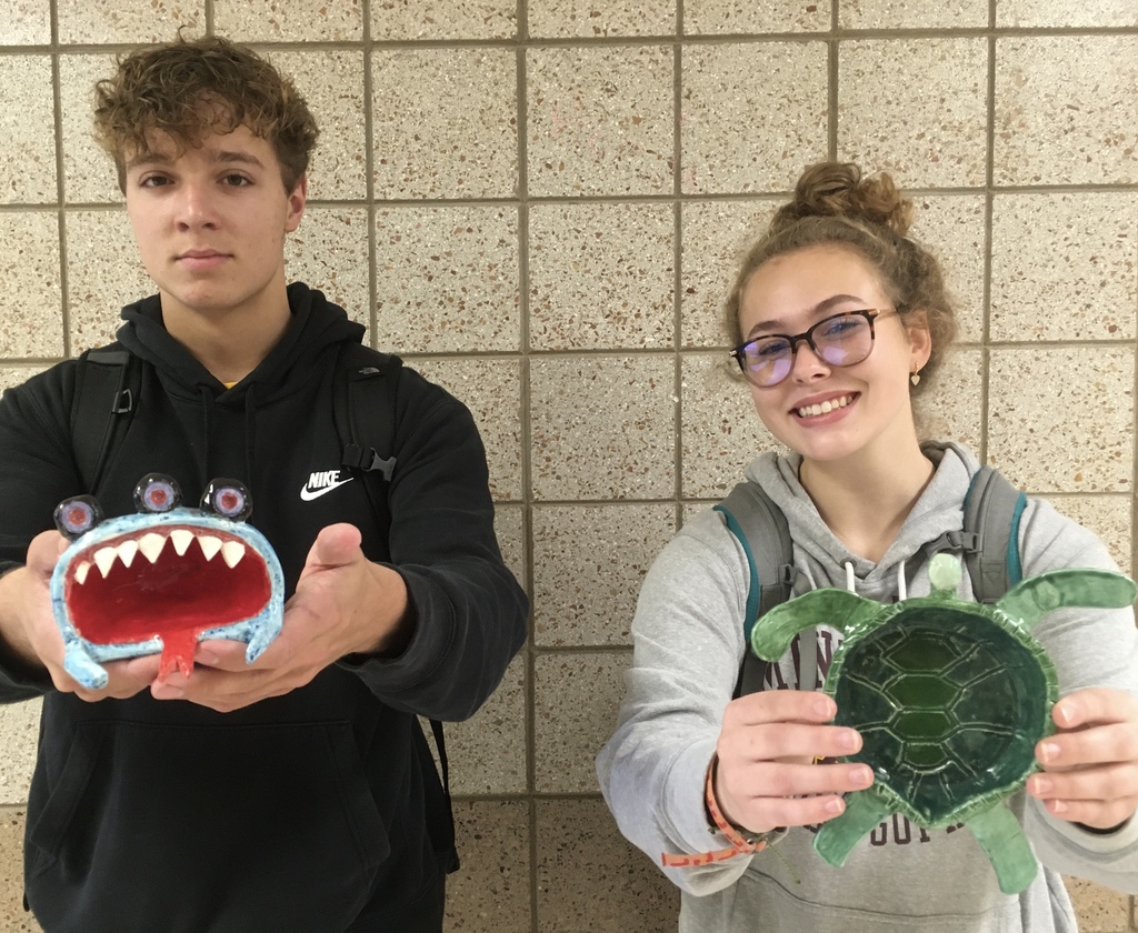 girl and boy with pinch pots of a turtle and a shark