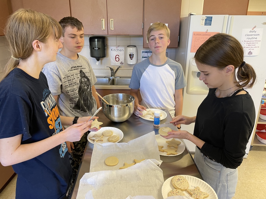 4 students frosting cookies