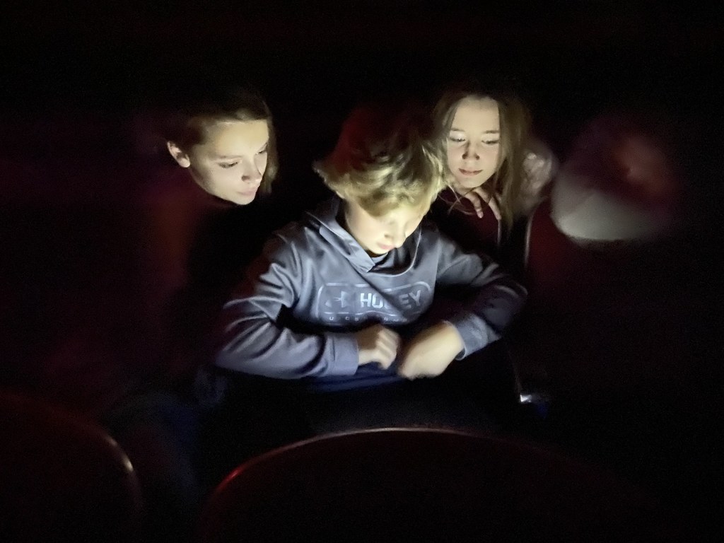 3 students looking at a computer in the dark