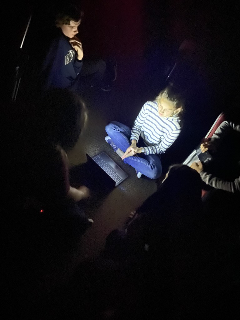 multiple students sitting on the floor in the dark