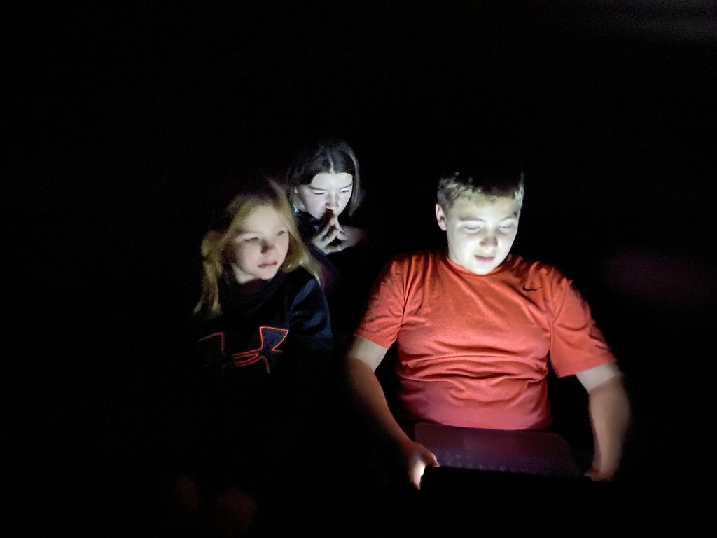 three students looking at a computer in the dark