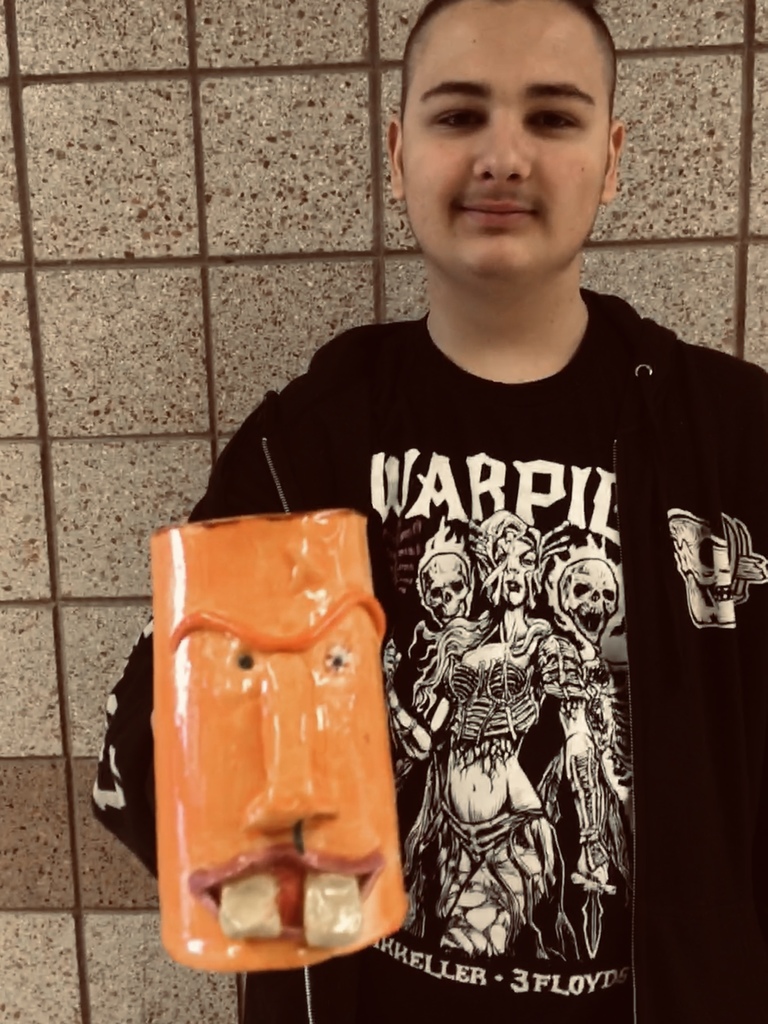 male student holding an orange face mug