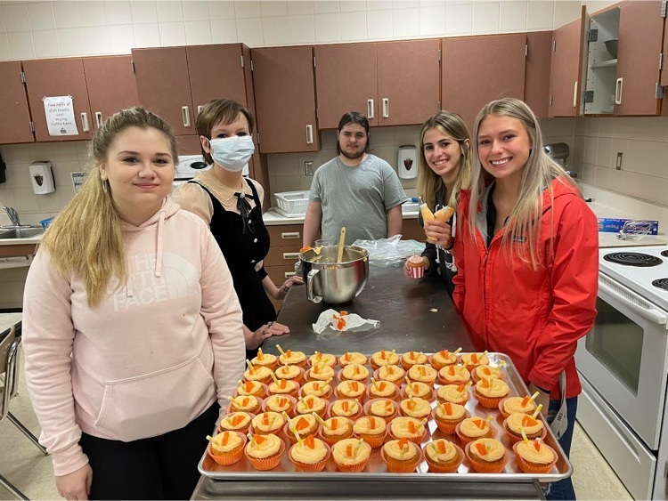 students next to orange cupcakes