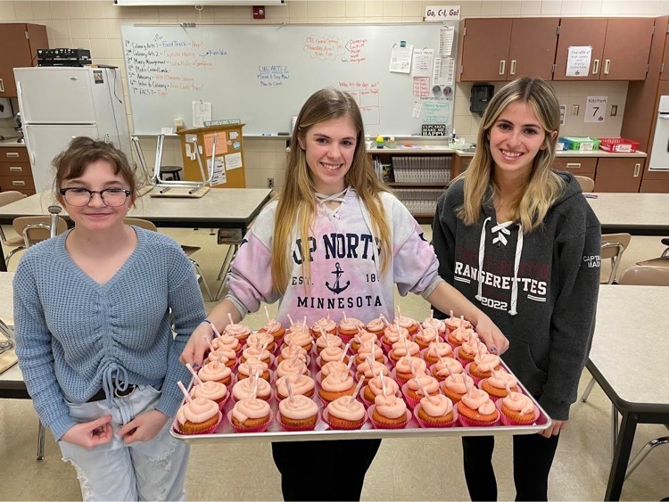 students holding a tray of pink cupcakes