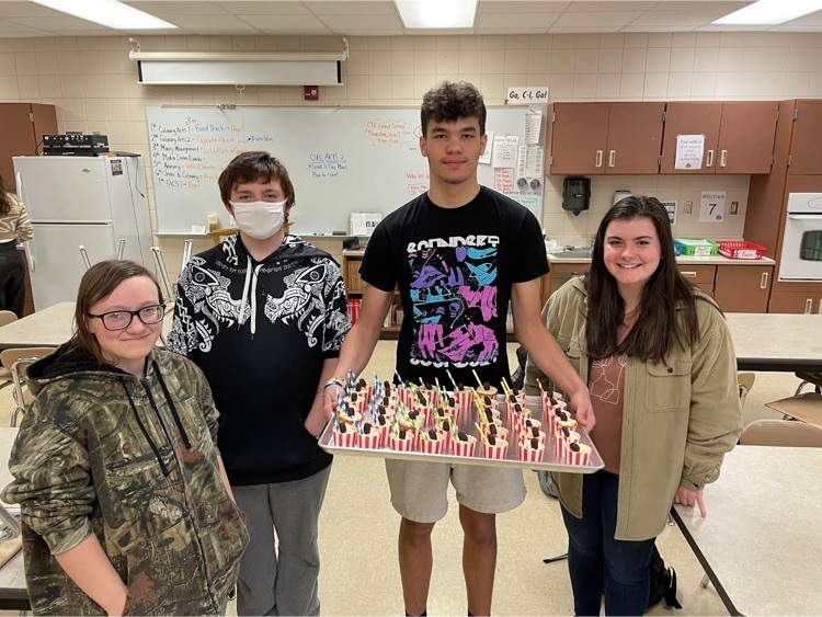 4 students holding cupcakes