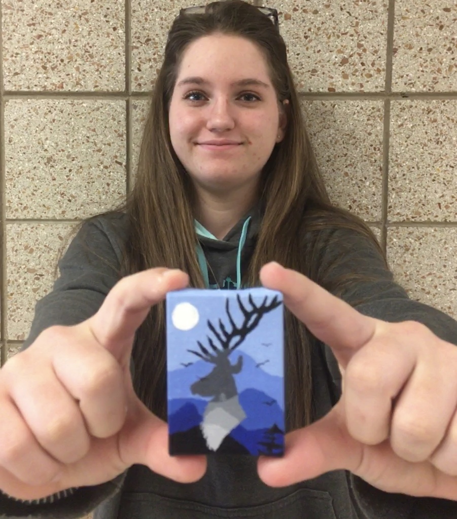 student holding a paiting of an elk