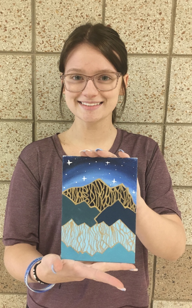 student holding a painting of a mountain