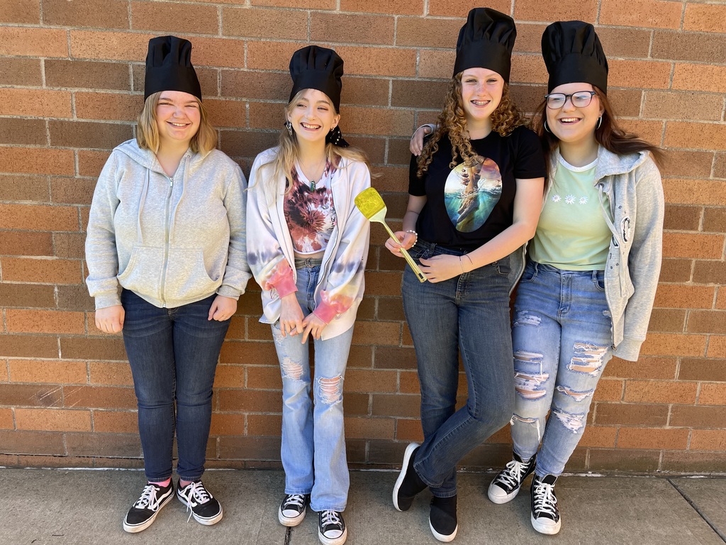 students with black chef hats and a golden spatula