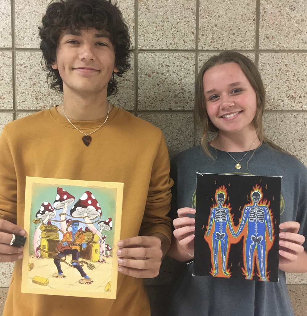 two students holding acrylic paintings