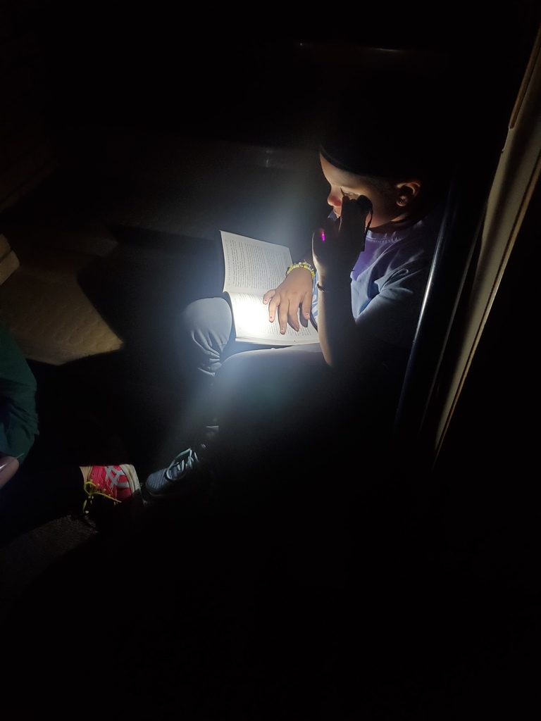 student with a flashlight reading in the dark