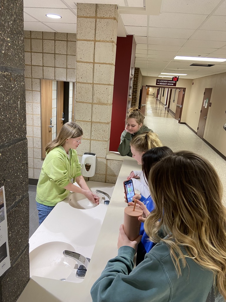 student washing her hands and students watching
