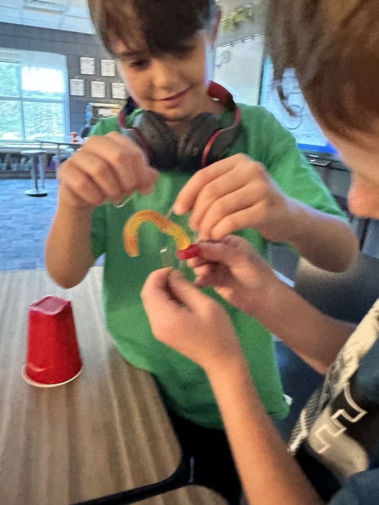 students holding a lifesaver a gummy worm and paperclips