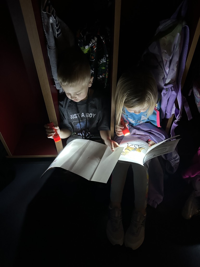 a boy and girl reading with flashlights