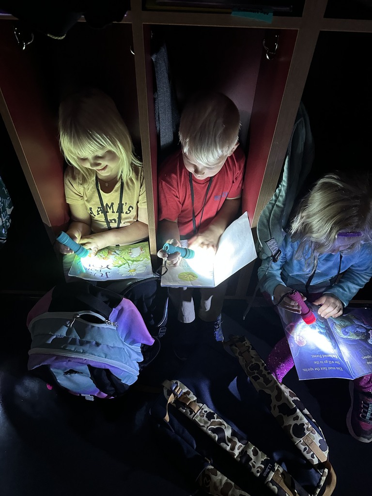 three students sitting in lockers with flashlights