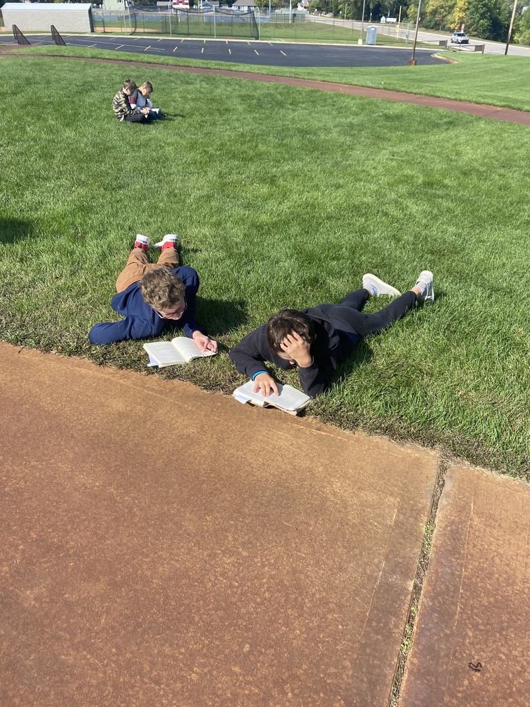 4 students sitting outside reading