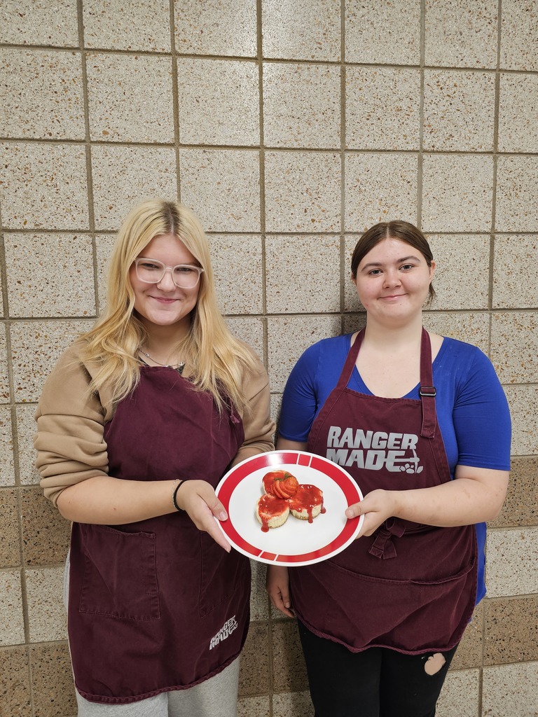 two students holding a plate of cheesecakes