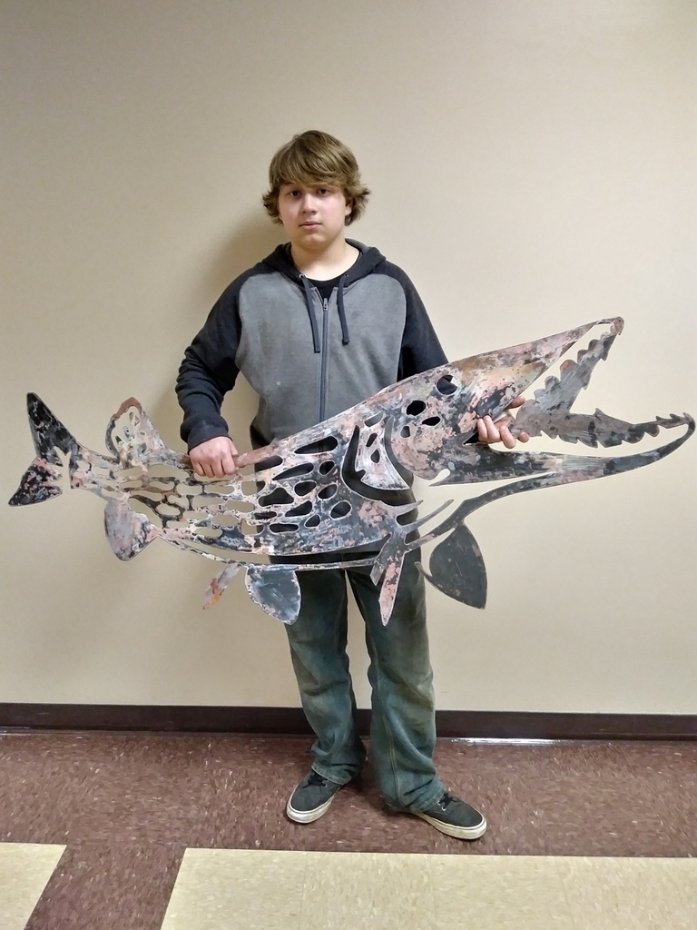 Student holding a metal fish